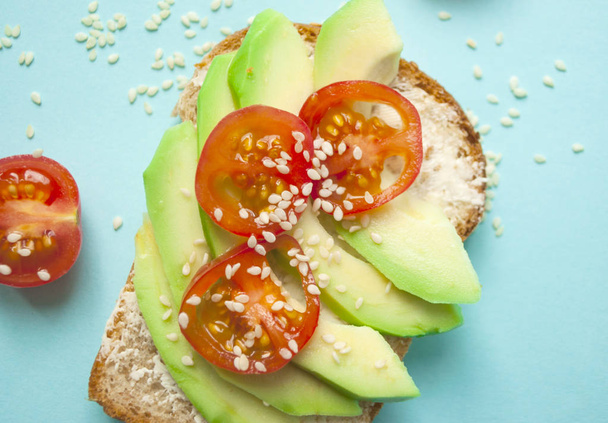 Fla lay of delicious toasts with sliced avocado, tomatoes and sesamum seeds. Healthy food concept. - Photo, Image