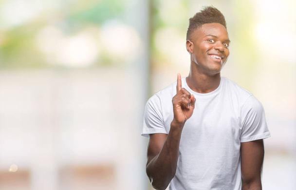 Jonge Afro-Amerikaanse man over geïsoleerde achtergrond vinger omhoog met succesvolle idee. Verlaten en gelukkig. Nummer één. - Foto, afbeelding