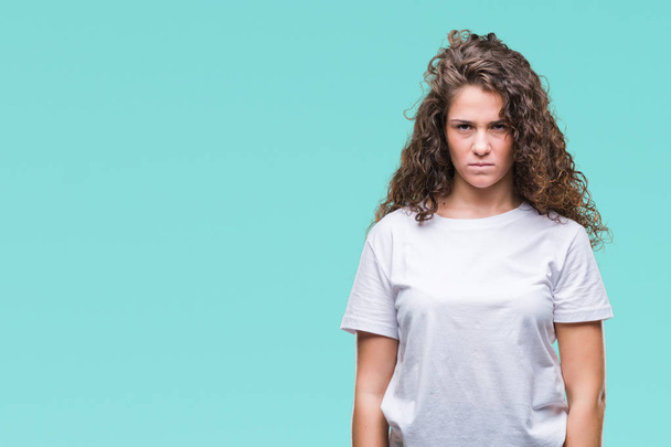 Beautiful brunette curly hair young girl wearing casual t-shirt over isolated background skeptic and nervous, frowning upset because of problem. Negative person. - Фото, изображение