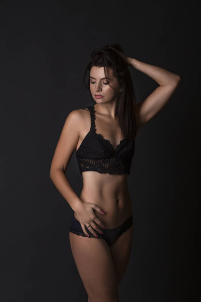 Sexy body of young attractive woman. Beautiful sporty lady in black bikini against dark background - Fotó, kép