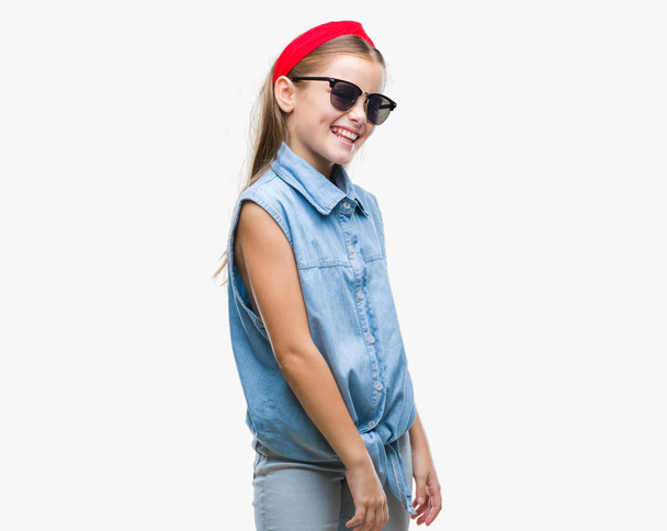 Młoda piękna dziewczyna noszenie okularów przeciwsłonecznych na białym tle, patrząc od strony z uśmiechem na twarzy, naturalne wyrażenie. Śmiejąc się pewnie. - Zdjęcie, obraz
