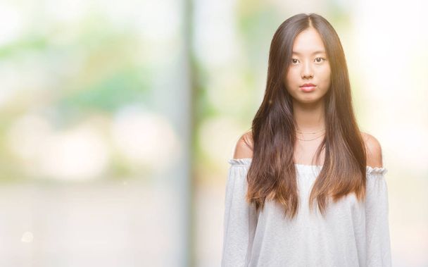 Young asian woman over isolated background with serious expression on face. Simple and natural looking at the camera. - Photo, image