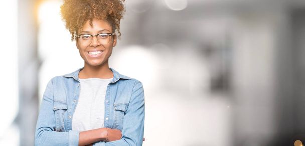 Krásná mladá africká americká žena nosí brýle nad, samostatný pozadí šťastný obličej s úsměvem překřížené paže při pohledu na fotoaparát. Pozitivní člověk. - Fotografie, Obrázek