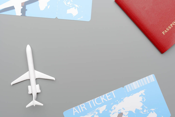 Close-up shot of small toy airplane lying near passport and plane tickets on gray background - Photo, Image