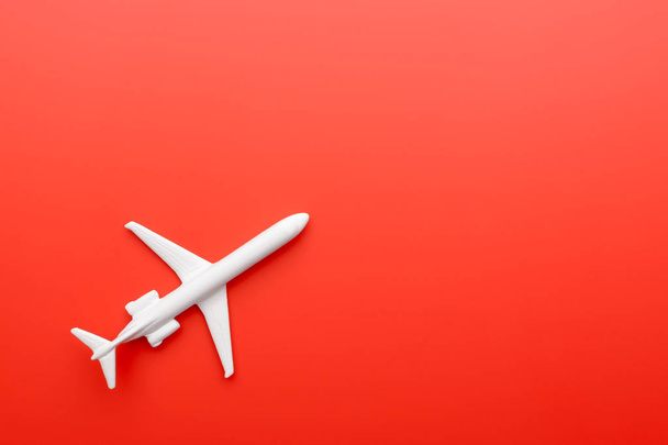 Сверху снимок крошечного игрушечного самолета белого цвета, лежащего на левой стороне ярко-красного фона
 - Фото, изображение