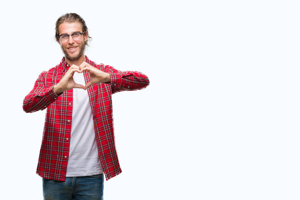 Young handsome man with long hair wearing glasses over isolated background smiling in love showing heart symbol and shape with hands. Romantic concept. - Zdjęcie, obraz