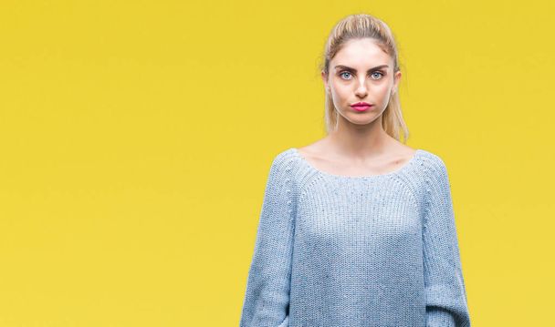Young beautiful blonde and blue eyes woman wearing winter sweater over isolated background with serious expression on face. Simple and natural looking at the camera. - Photo, Image