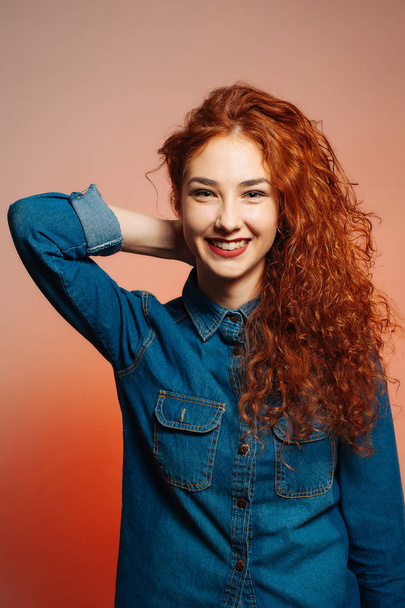 Портрет молодой веселой женщины с длинными рыжими вьющимися волосами, улыбающейся
 - Фото, изображение