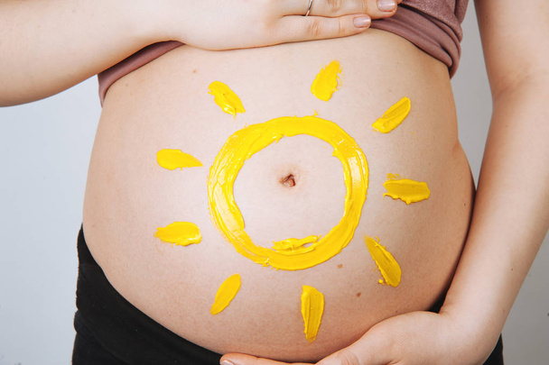 Egy terhes nő, egy kis nap belsejében a has has-fotó - Fotó, kép