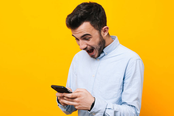 Portrait de jeune homme excité qui joue à des jeux sur smartphone
 - Photo, image