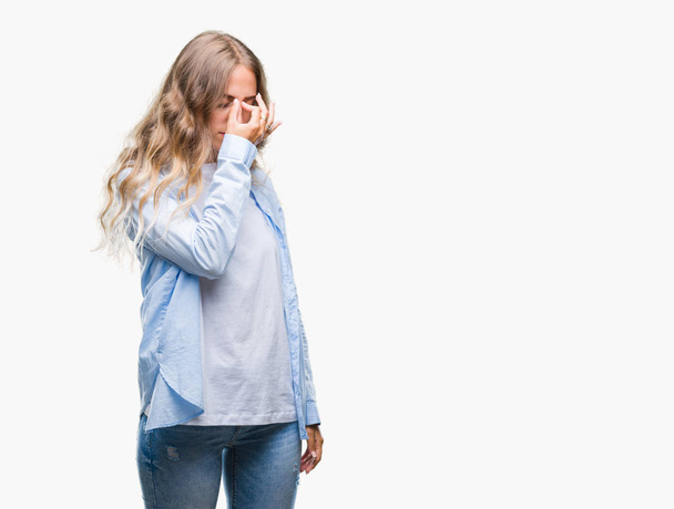 Beautiful young blonde woman over isolated background tired rubbing nose and eyes feeling fatigue and headache. Stress and frustration concept. - Foto, Bild