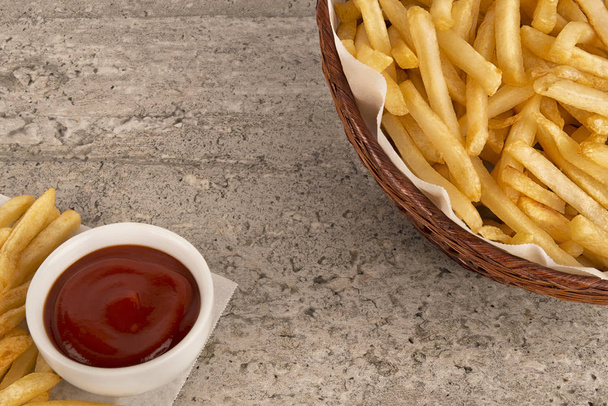 Cesta de patatas fritas con salsa de tomate sobre fondo de hormigón. Sal, ketchup y botella de mostaza. De cerca.
. - Foto, imagen