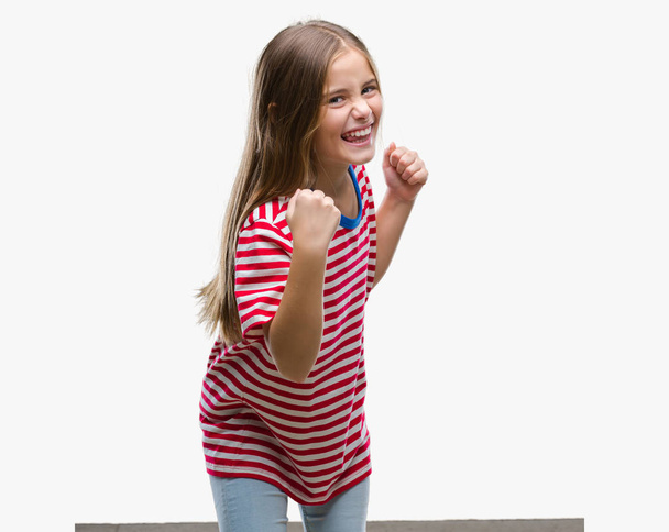 Young beautiful girl over isolated background very happy and excited doing winner gesture with arms raised, smiling and screaming for success. Celebration concept. - Foto, imagen