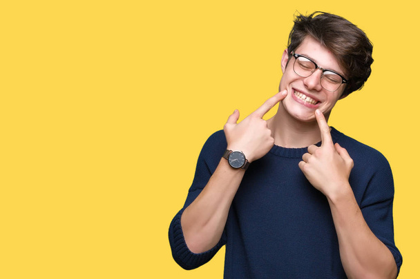 Mladý pohledný muž nosí brýle izolované pozadí s úsměvem sebevědomá ukazující a ukazující prsty zuby a ústa. Koncepce zdraví. - Fotografie, Obrázek