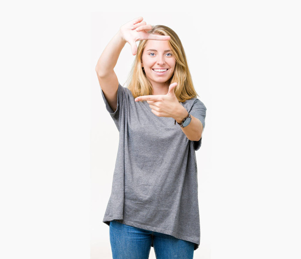 Hermosa mujer joven con camiseta casual de gran tamaño sobre fondo aislado sonriendo haciendo marco con manos y dedos con la cara feliz. Concepto de creatividad y fotografía
. - Foto, Imagen