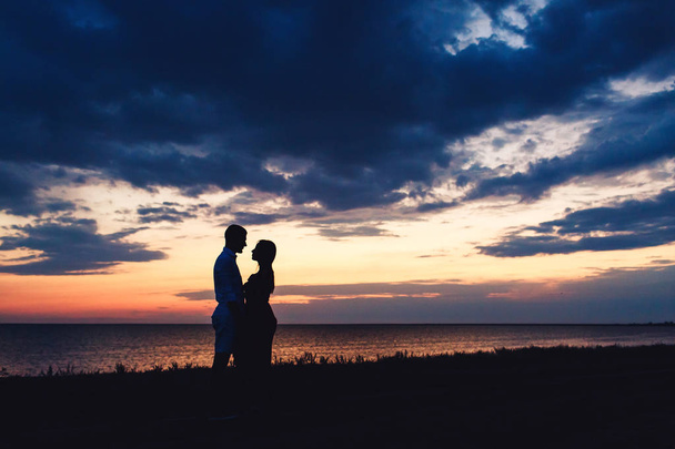 Sziluettjét fotó egy szerelmes pár a háttérben a gyönyörű naplemente ég és a tenger. - Fotó, kép