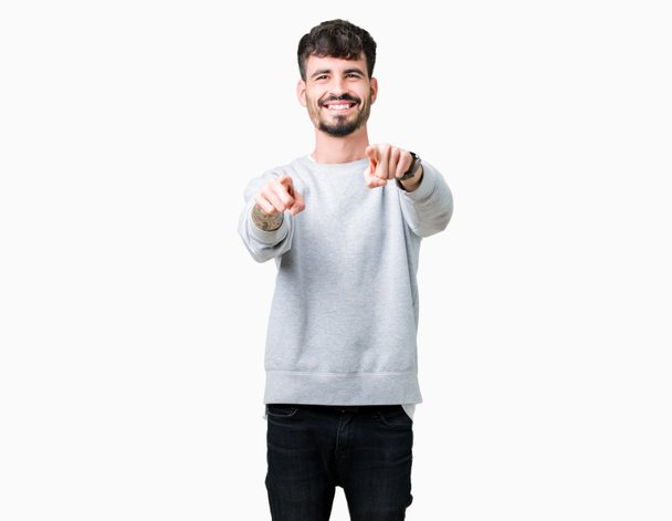 Jóképű fiatalember visel pulóver felső elszigetelt háttér mutatva-hoz ön, és a kamera ujjaival, pozitív és vidám mosolygós - Fotó, kép