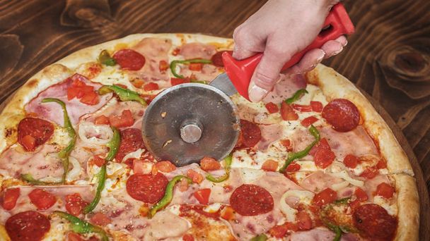 Cutting pepperoni pizza on slices with special knife. Tasty fast food italian traditional - Fotoğraf, Görsel
