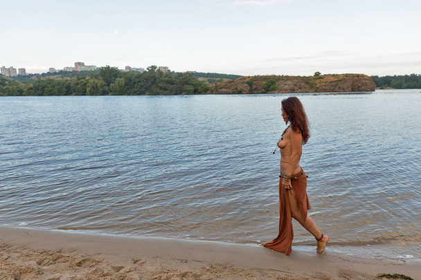 mladí kavkazské krásné nahé Amazon žena chůze podél řeky pláži při západu slunce - Fotografie, Obrázek