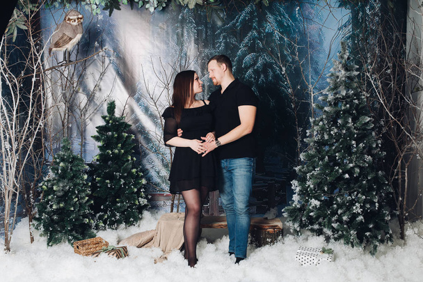 Man and pregnant woman posing in decorated winter studio. - Photo, Image