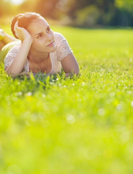 Thoughtful girl laying on meadow - Foto, imagen