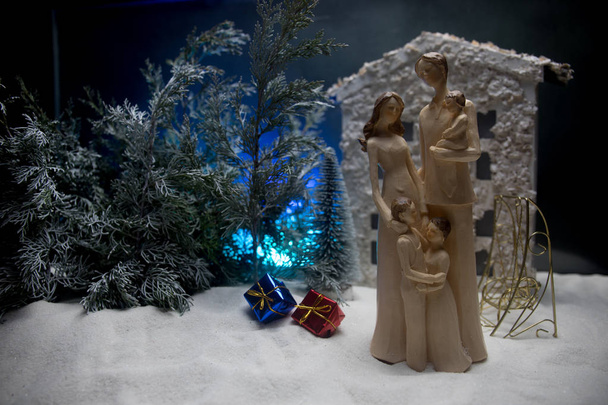 Hračka dekorace kresby. Šťastný nový rok oslava, mladá rodina stojící v přední dvoře ve sněhu se stromy a domeček pro malé panenky. Selektivní fokus - Fotografie, Obrázek