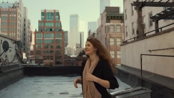 Back View Shot of Beautiful Woman Walking on a Roof, Turning Around and Smiling Wind Shuffles Her Long Red Hair. Urban Cityscape View of New York City with Great Skyscrapers and Buildings. - Materiał filmowy, wideo