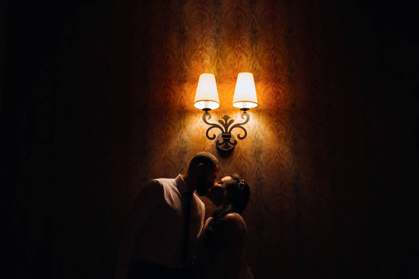 ランタンが付いている壁の背景にキスした新婚夫婦のプロフィール - 写真・画像