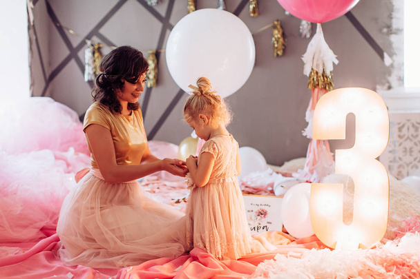 Happy mother with cute daughter in room on Birthday party.   - Photo, Image