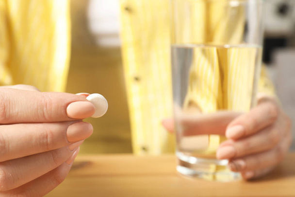 Woman with pill and glass of water at table, closeup - Foto, immagini