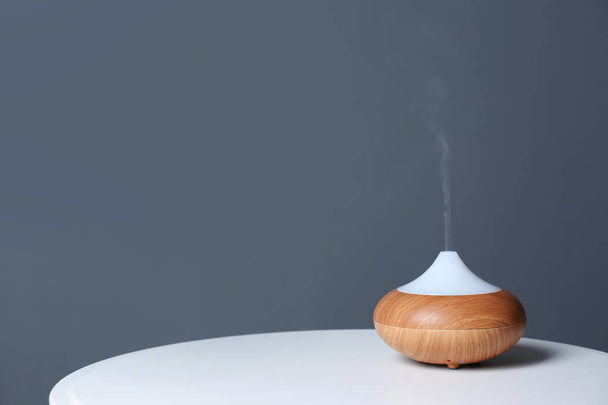Aroma oil diffuser lamp on table against gray background. Space for text - Фото, изображение