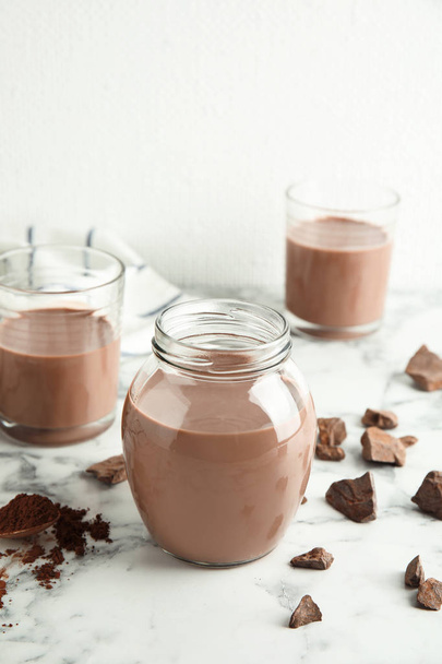 Glassware with tasty chocolate milk on marble table. Dairy drink - Foto, Imagem