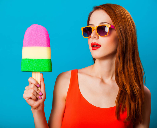 rusovláska dívka s hračkou zmrzliny na modrém pozadí. - Fotografie, Obrázek