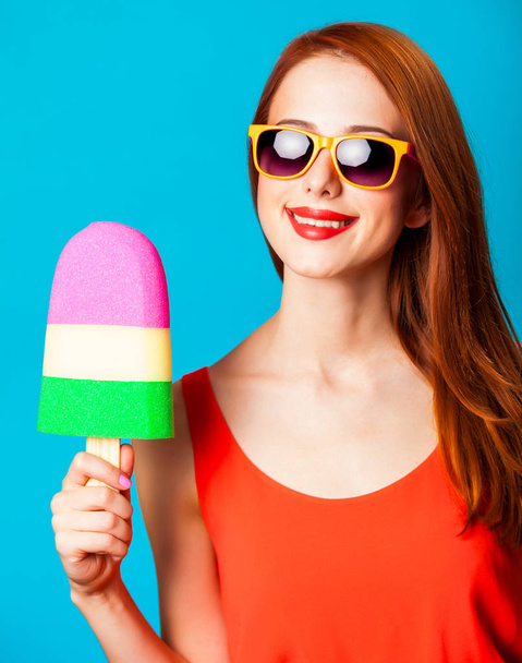 Redhead girl with toy ice cream on blue background. - Fotoğraf, Görsel
