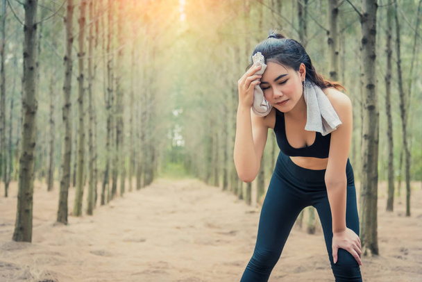 Asian beauty woman wiping the sweat in forest. Towel and sweat elements. Sport and Healthy concept. Jogging and Running concept. Relax and take a break theme. Outdoors activity theme. - Photo, Image