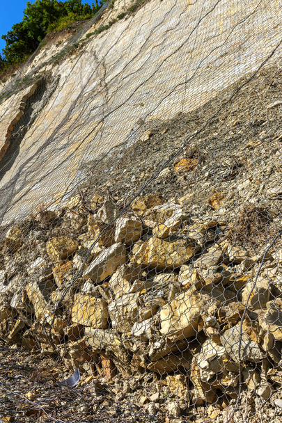 Suojelua maanvyörymältä. Murskattu kivi, sora, kivi elementtejä maiseman suunnittelu metalliverkossa suojaa maanvyörymä ja eroosio tulva-vedet, meren aallot. Rannikon vahvistaminen
 - Valokuva, kuva