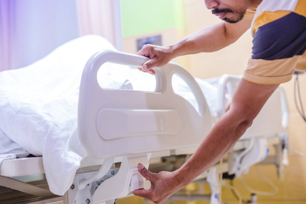 manos del hombre ajustar la cama del paciente en el hospital
. - Foto, Imagen