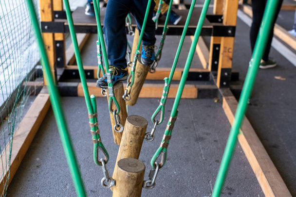enfants marchant sur des troncs suspendus par des cordes dans un parc d'aventure
. - Photo, image