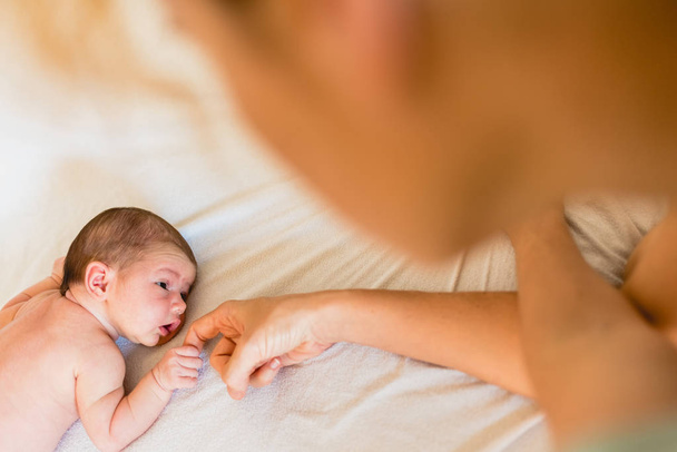 Newborn baby holding his mother's hands tenderly. - Fotografie, Obrázek