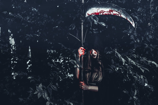 Жіночий демон відьом з криваві reaper стоячи перед таємниця тлі лісу. Хеллоуїн і релігійних концепції. Демон ангел і сатана теми. - Фото, зображення