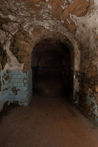 Een oude verlaten tunnel in een ondergrondse wijnkelder. Toegang tot de catacomben. Oude stenen fort van Dungeon. Als creatieve achtergrond voor de enscenering van donkere design. Mystieke interieur van oude dungeon - Foto, afbeelding
