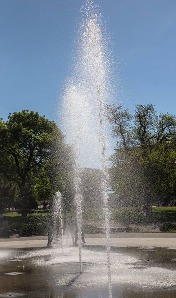 明るい晴れた日の夏の都市公園で高い水市泉。市泉の水の飛散は明るいカラフルなレインボーに太陽の光を屈折します。 - 写真・画像