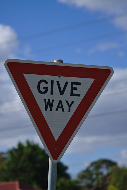 Закрыть вид знака "Дай дорогу" в форме красного треугольника и на синем фоне неба
 - Фото, изображение