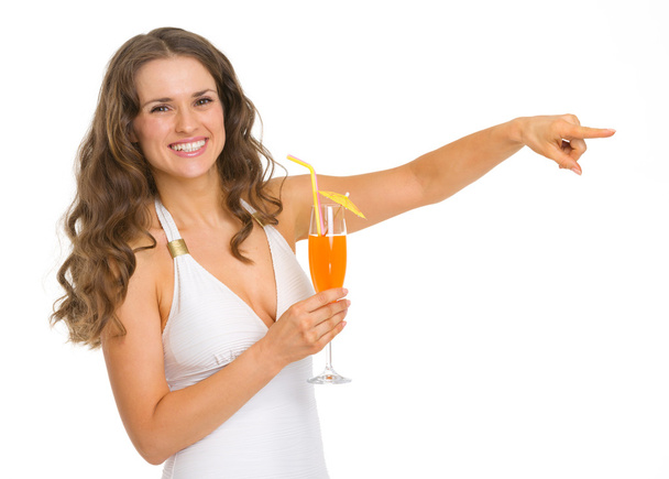 Smiling young woman in swimsuit with cocktail pointing on copy s - Фото, зображення