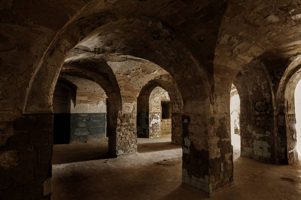 Een oude verlaten tunnel in een ondergrondse wijnkelder. Toegang tot de catacomben. Oude stenen fort van Dungeon. Als creatieve achtergrond voor de enscenering van donkere design. Mystieke interieur van oude dungeon - Foto, afbeelding