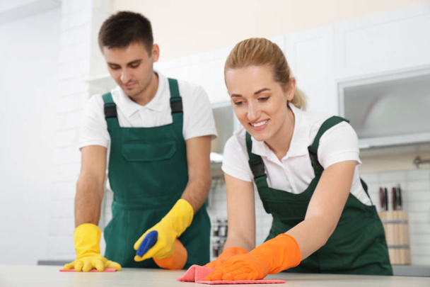 Male janitor cleaning oven tray with sponge in kitchen - Foto, Imagen