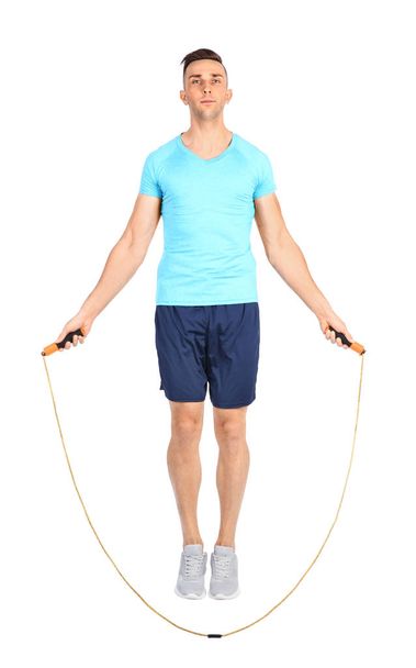 Full length portrait of young sportive man training with jump rope on white background - Valokuva, kuva