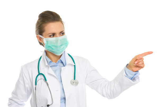 Medical doctor woman in mask pointing on copy space - Foto, imagen