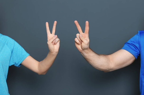 Man and woman showing victory gestures on color background - Fotoğraf, Görsel