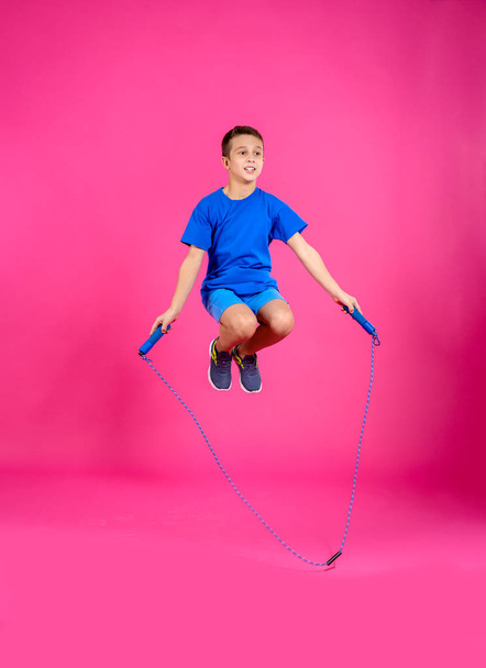 Full length portrait of boy jumping rope on color background - Foto, afbeelding